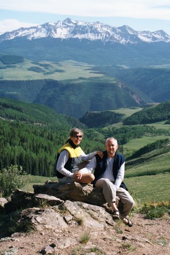 Penny and Rob sitting on a rock with mountains behind